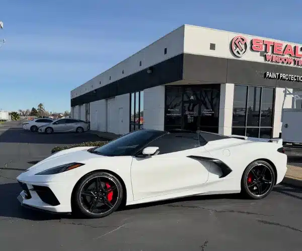 view of a luxury car parked inside a brightly lit detailing garage, showcasing a flawless, high-gloss finish after a paint protection film installation